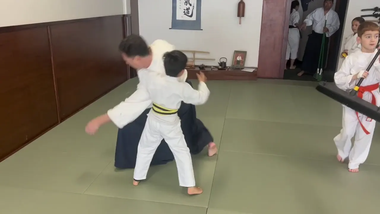 Youth, family, and weapons practice inside the dojo